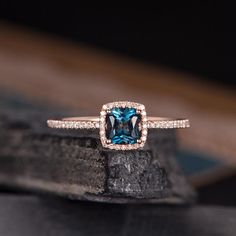 an engagement ring with a blue topazte surrounded by white and rose gold diamonds