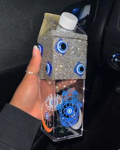 a person holding a bottle in their hand with an eyeball design on the inside