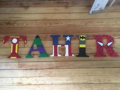 wooden letters spelling out the word faith on a wood floor with batman and spiderman