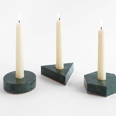 three candles sitting on top of green marble bases