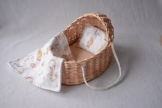 a wicker basket with two baby blankets in it on a white tableclothed surface