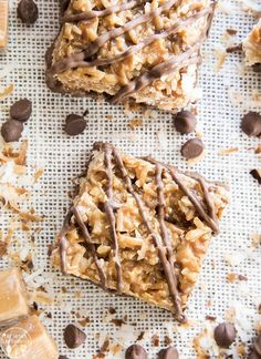 three bars with chocolate drizzled on top and some nuts scattered around them