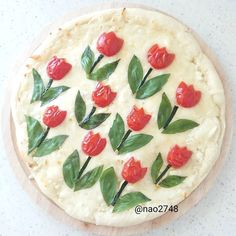 a pizza decorated with red flowers and green leaves