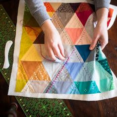 a woman is working on a colorful quilt