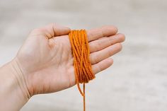 a hand holding an orange string in it's palm