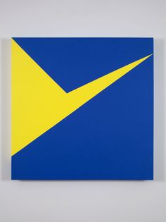 a blue and yellow square with an arrow on the bottom, against a white wall