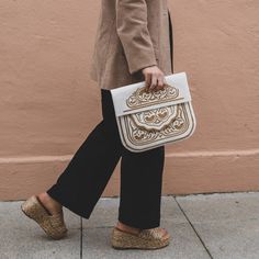 In Morocco, hand embroidery serves as a thread connecting generations, with mothers teaching daughters the craft. Embroidered designs can be found on various items in the souks—from handkerchiefs to poufs and bags—and the designs differ from city to city. This satchel, the perfect size for books, has proven itself a versatile companion for any adventure. 10" tall, 11" wide Detachable shoulder strap Embroidered leather Chic Beige Embroidered Bags, Cream Embroidered Shoulder Bag For Travel, Embroidered Cream Shoulder Bag For Travel, Chic White Embroidered Bag, Chic White Embroidered Shoulder Bag, Chic Beige Embroidered Shoulder Bag, Chic Embroidered Beige Shoulder Bag, Traditional White Bags With Intricate Embroidery, Embroidered Satchel With Double Handle