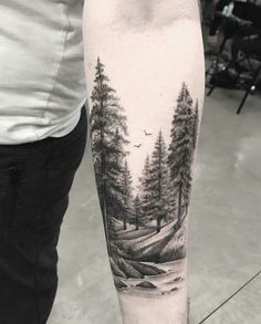 a man's arm with a black and white landscape tattoo on it