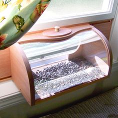 a window sill with a bird feeder in it's center and flowers on the outside