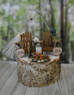 a wooden table topped with a cake covered in frosting and wood slices next to a fishing pole