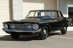 an old black car parked in front of a building