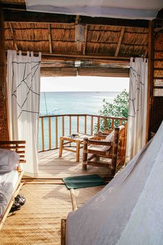 a bed sitting on top of a wooden floor next to an open door leading to the ocean