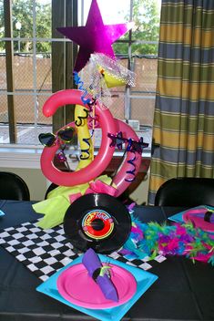 a table topped with plates and balloons in front of a window