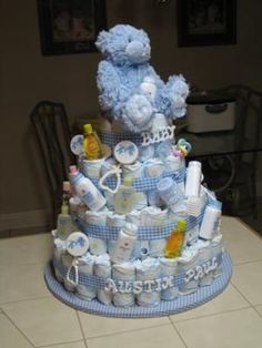 a blue baby shower cake with teddy bears on top and diapers all around it