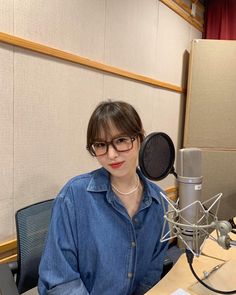 a woman sitting at a desk with a microphone in front of her and a book on the table