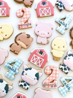 cookies decorated with farm animals and numbers are displayed on a white tablecloth for the first birthday boy or girl