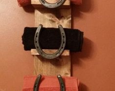 three pieces of wood mounted to the side of a wall with metal rings on them