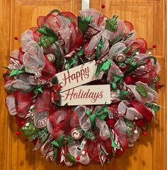 a holiday wreath hanging on the front door with happy holidays written on it's side