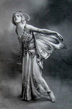 a woman in a long dress is posing with her arms spread out to the side