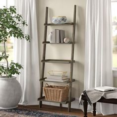 a black leaning shelf with books on it next to a window and a plant in a vase