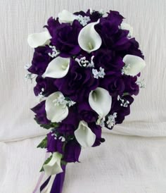 a bridal bouquet with white calla lilies and purple orchids is displayed