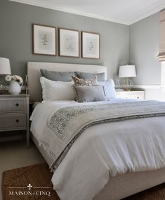 a white bed sitting in a bedroom next to two framed pictures