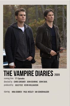 two men standing next to each other in front of a poster for the vampire diaries