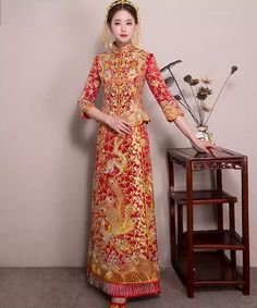 Traditional Festive Cheongsam For Ceremony, Traditional Brocade Dress With Gold Embroidery, Traditional Long Sleeve Gown For Banquet, Traditional Festive Ceremonial Cheongsam, Ceremonial Festival Brocade Dresses, Ceremonial Brocade Dresses For Festivals, Ceremonial Gold Gown, Traditional Festive Cheongsam For Ceremonial Occasions, Traditional Cheongsam For Ceremony