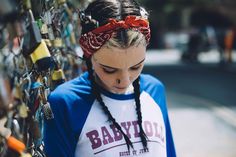 a young woman with braids standing next to a wall covered in padlocks