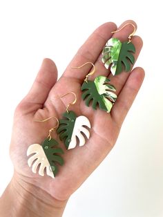 the palm leaf earrings are green, white and black with gold accents on them as if they were made from wood