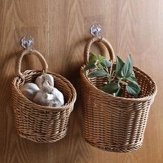 two wicker baskets with plants in them hanging on a wall next to each other