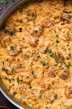 a pan filled with pasta and meat covered in cheese sauce on top of a wooden table