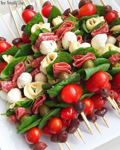 several skewers filled with different types of food on toothpicks and tomatoes