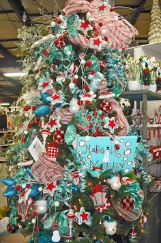 a christmas tree decorated with red, white and blue ribbon bows is in a store