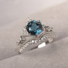 a ring with a blue topaz surrounded by white diamonds on a gray surface,