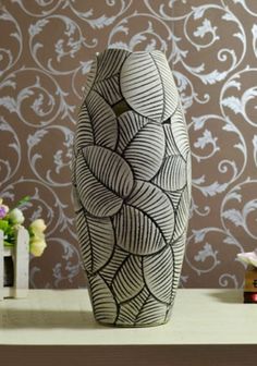 a white vase sitting on top of a table next to a wallpapered wall