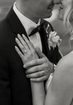 black and white photograph of a bride and groom embracing each other with their wedding rings on their fingers