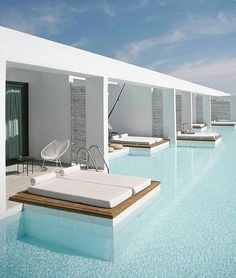 an outdoor swimming pool with lounge chairs next to it and blue sky in the background