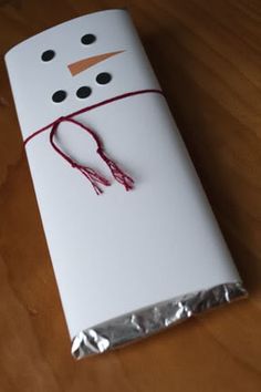 a white box with a snowman made out of paper on top of a wooden table