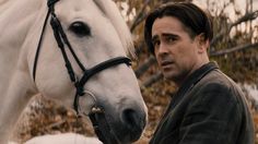 a man standing next to a white horse