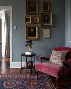 a living room filled with furniture and pictures on the wall behind a chair next to a table