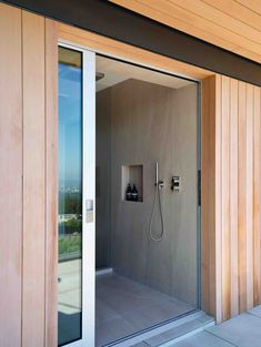 an open shower in the corner of a room with sliding glass doors and wood paneling