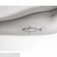 a black and white photo of a fish tattoo on the left arm, with an outline of a fish