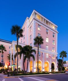 the hotel is lit up at night with palm trees