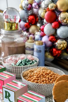 a table topped with bowls filled with food next to christmas ornaments and candy bars on top of it