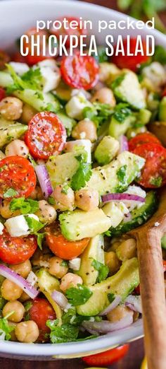 a salad with chickpea, cucumber and tomatoes in a white bowl