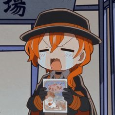 an orange haired woman wearing a black hat and coat holding a card in front of her face