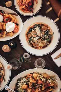 a table topped with plates and bowls filled with different types of food next to wine glasses