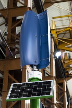 a solar panel mounted on top of a green pole in a building with stairs and scaffolding