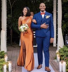 a man and woman are walking down the aisle with candles in front of their heads